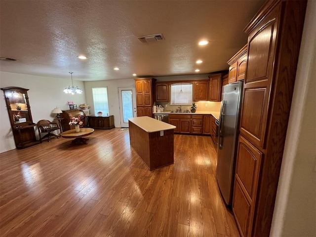 kitchen featuring a center island, hanging light fixtures, hardwood / wood-style flooring, a textured ceiling, and stainless steel appliances