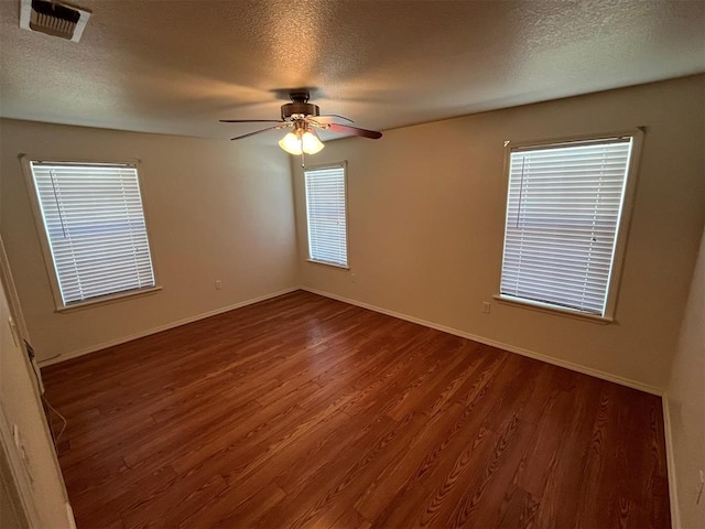 spare room featuring a textured ceiling, plenty of natural light, and dark wood-type flooring