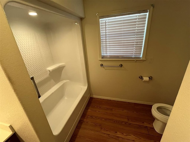 bathroom featuring hardwood / wood-style floors, a bath, and toilet