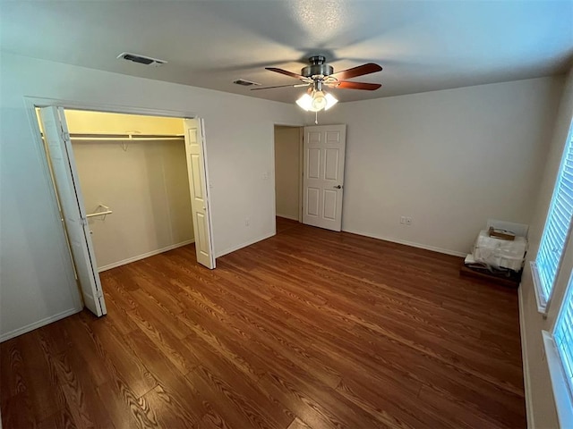 unfurnished bedroom with ceiling fan, dark hardwood / wood-style flooring, and a closet