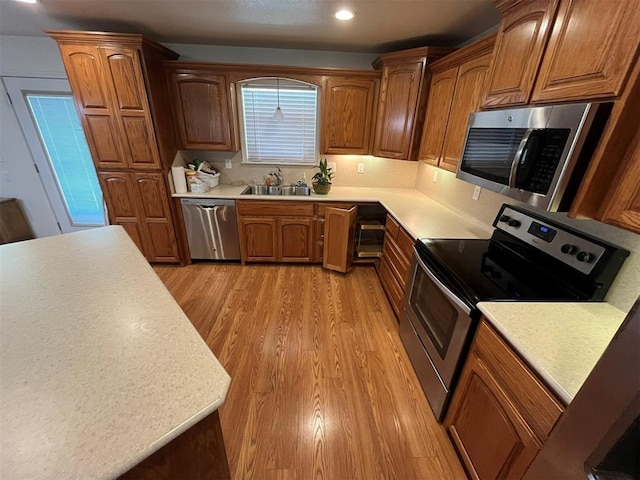 208 N Kay Dr, Broken Bow, OK 74728 - kitchen featuring appliances with stainless steel finishes, a sink, light wood finished floors, light countertops, and brown cabinetry