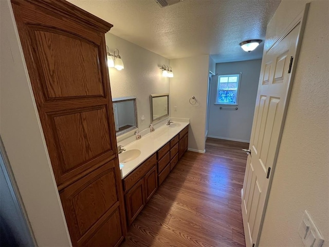 208 N Kay Dr, Broken Bow, OK 74728 - full bathroom featuring a textured ceiling, wood finished floors, double vanity, a shower, and baseboards