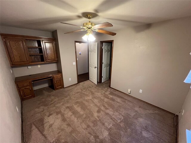 unfurnished bedroom with ceiling fan, light colored carpet, and built in desk