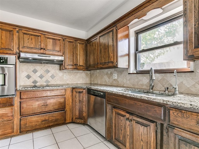 kitchen featuring light stone countertops, appliances with stainless steel finishes, light tile patterned floors, and sink