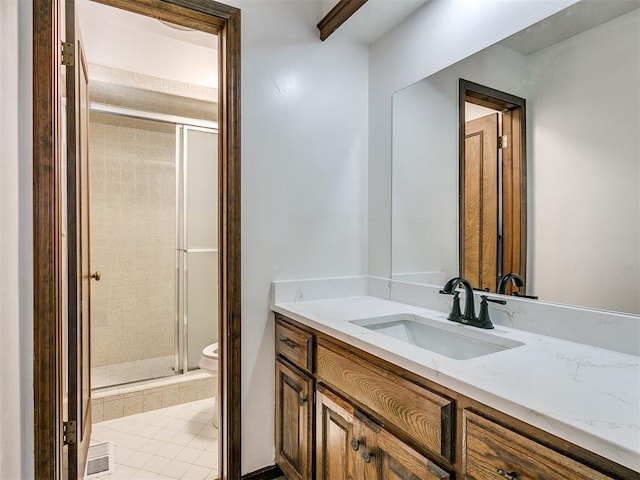 bathroom with tile patterned flooring, vanity, toilet, and a shower with door