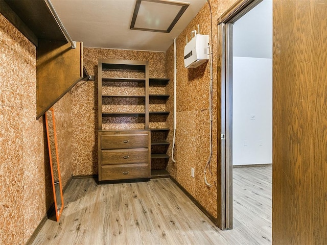 spacious closet with a wall mounted air conditioner and light wood-type flooring