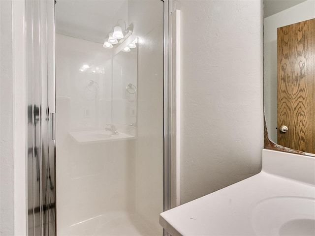 bathroom with a shower with door and vanity