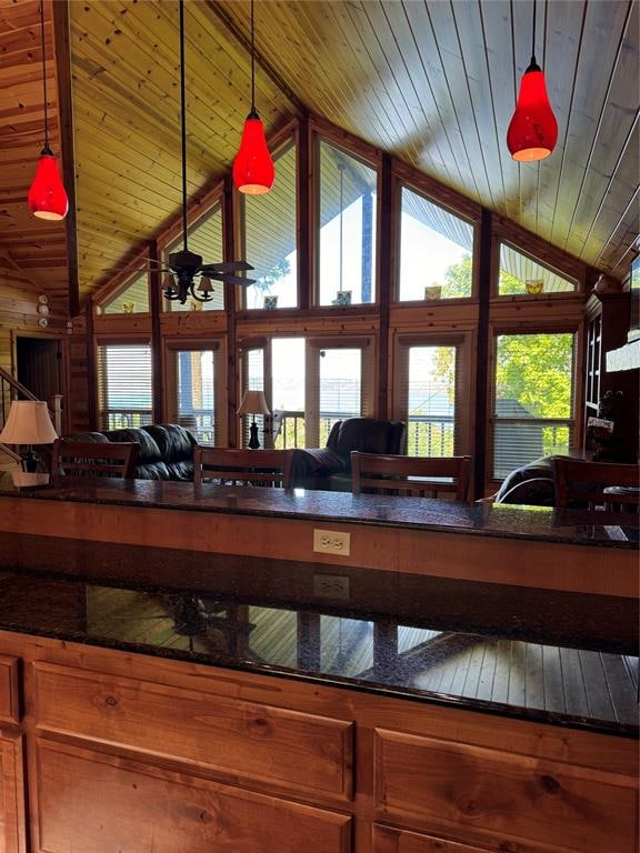 interior space featuring decorative light fixtures, ceiling fan, lofted ceiling, and wood ceiling