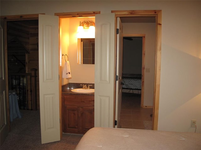 bedroom featuring ensuite bathroom, sink, tile patterned flooring, a spacious closet, and a closet