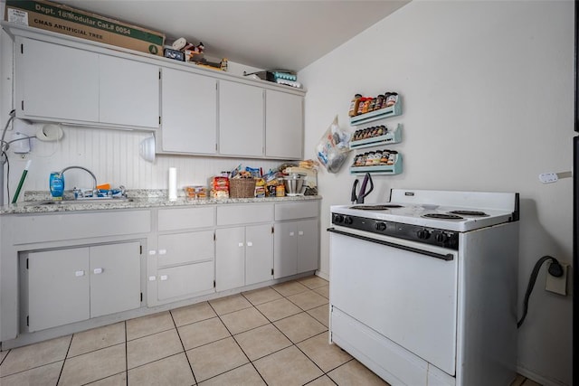 kitchen with white range with gas cooktop, sink, white cabinets, and light tile patterned flooring