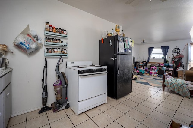 kitchen with black refrigerator, light tile patterned flooring, and white range