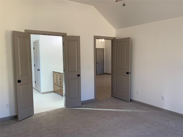 unfurnished bedroom with vaulted ceiling and light carpet