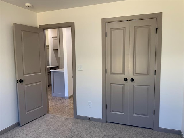 unfurnished bedroom with light colored carpet and a closet