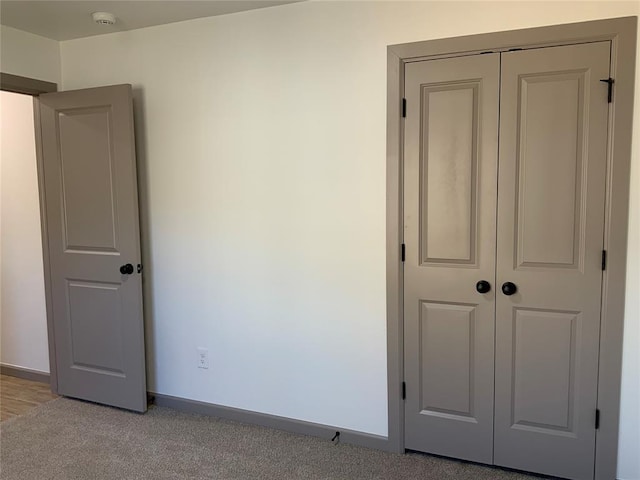 unfurnished bedroom featuring light carpet and a closet