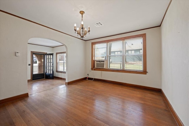 empty room with hardwood / wood-style floors, cooling unit, a chandelier, and ornamental molding