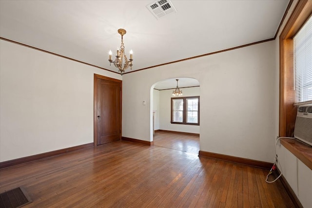 empty room with crown molding, hardwood / wood-style floors, and an inviting chandelier