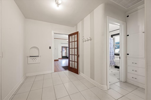 corridor featuring light tile patterned flooring and french doors