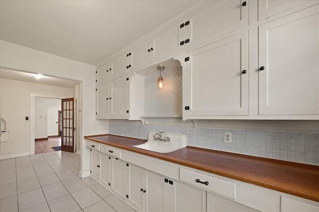 kitchen with decorative backsplash, sink, decorative light fixtures, butcher block countertops, and white cabinetry