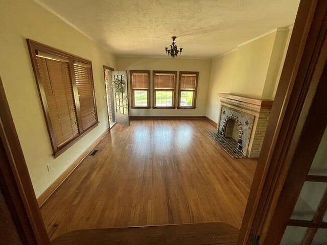 unfurnished living room featuring hardwood / wood-style flooring, a notable chandelier, ornamental molding, and a textured ceiling