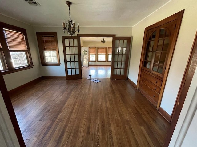 unfurnished dining area featuring french doors, dark hardwood / wood-style flooring, an inviting chandelier, and plenty of natural light