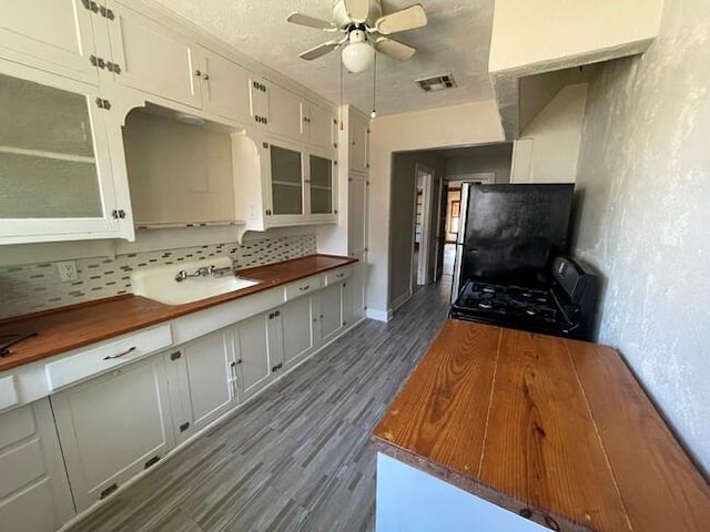 kitchen with backsplash, black appliances, white cabinets, ceiling fan, and dark hardwood / wood-style flooring