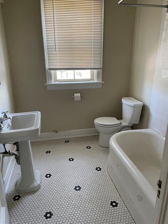 bathroom featuring tile patterned floors, a washtub, and toilet