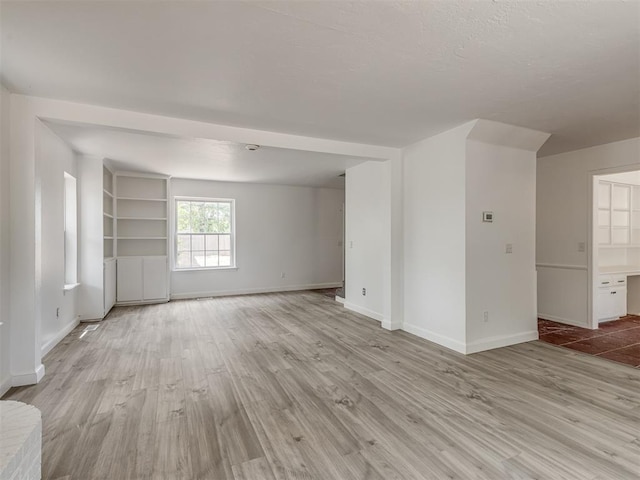 empty room with light hardwood / wood-style flooring and built in features