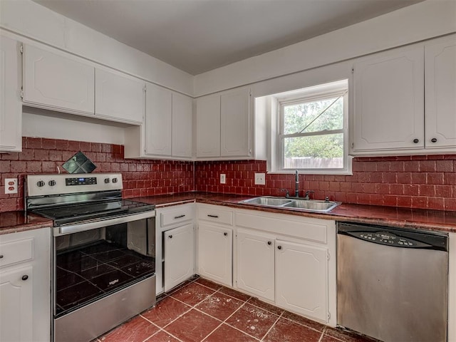 kitchen with white cabinetry, sink, stainless steel appliances, decorative backsplash, and dark tile patterned flooring