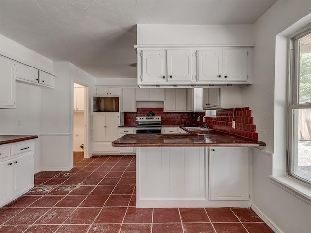 kitchen featuring kitchen peninsula, white cabinetry, stainless steel range with electric cooktop, and tasteful backsplash