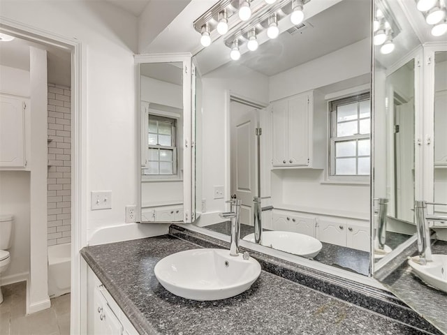 full bathroom with tile patterned floors, vanity, tiled shower / bath, and toilet