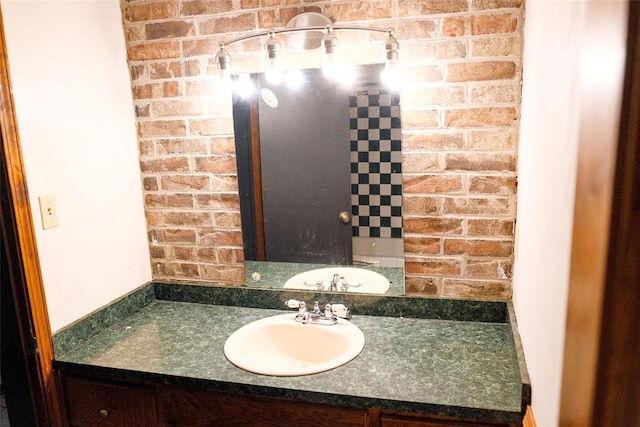 bathroom featuring vanity and brick wall