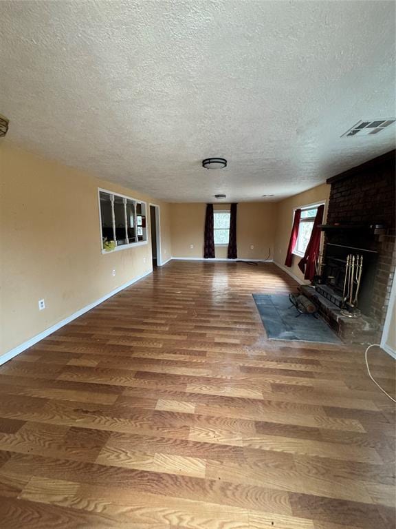 unfurnished living room featuring hardwood / wood-style floors, a fireplace, and a textured ceiling