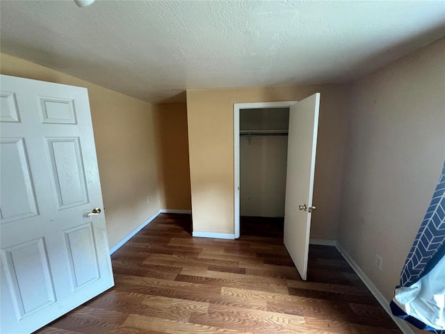 unfurnished bedroom with dark wood-type flooring and a textured ceiling