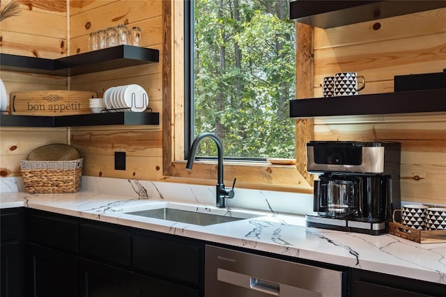 kitchen featuring light stone counters, stainless steel dishwasher, and sink