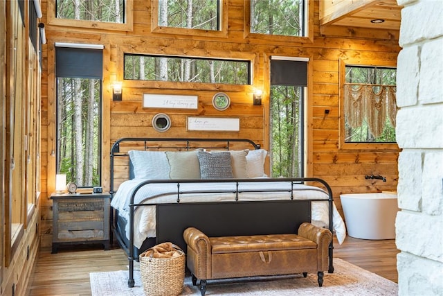 bedroom featuring beamed ceiling, light hardwood / wood-style floors, and a high ceiling