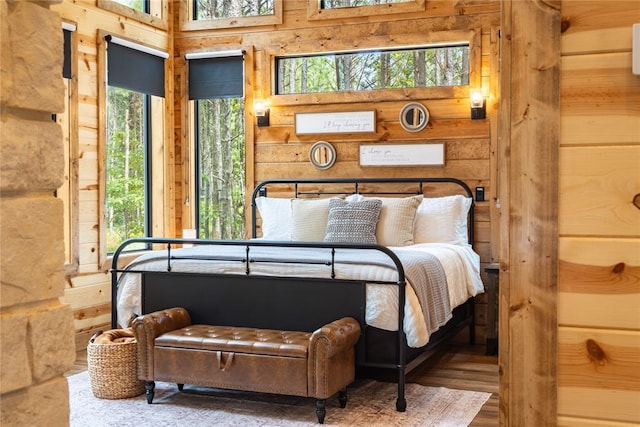 bedroom featuring wood-type flooring, a high ceiling, and multiple windows