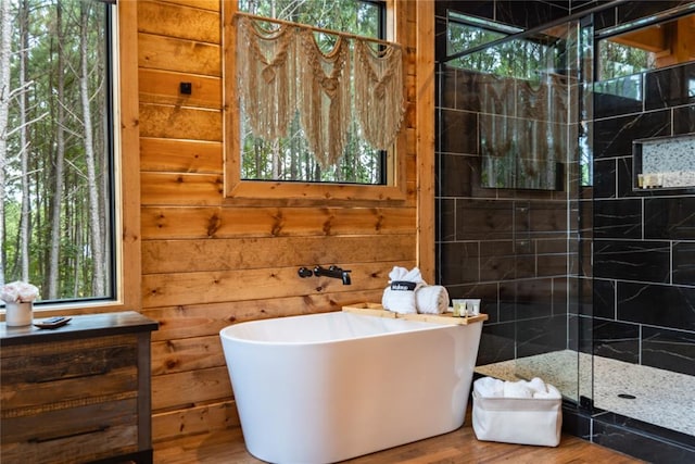 bathroom featuring hardwood / wood-style floors, shower with separate bathtub, plenty of natural light, and wood walls