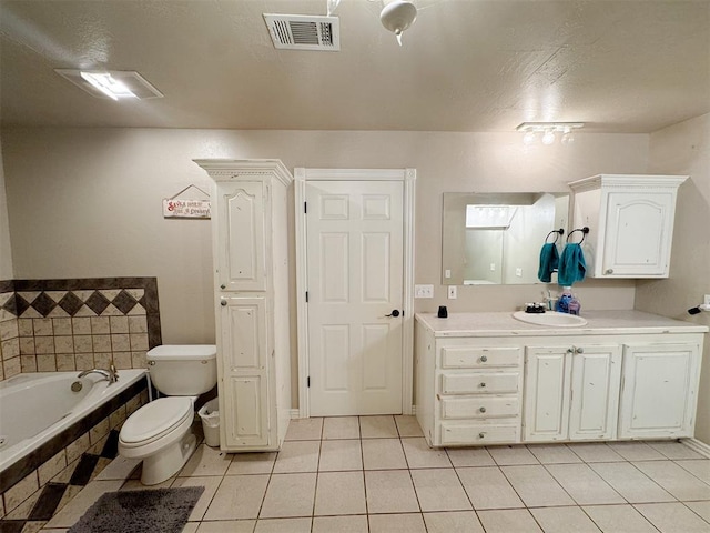 bathroom with tile patterned flooring, vanity, tiled bath, and toilet