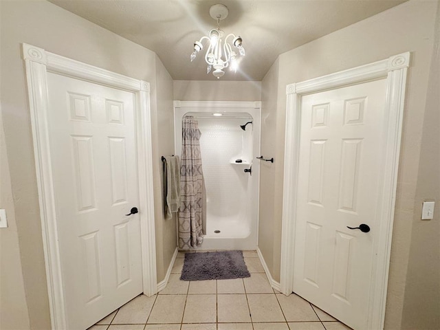 interior space with tile patterned flooring, tiled shower, and a chandelier