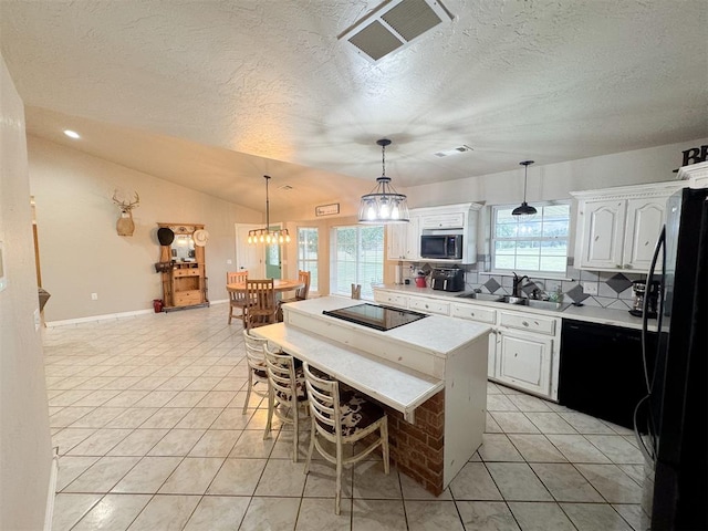 kitchen with white cabinetry, sink, lofted ceiling, a kitchen island, and black appliances