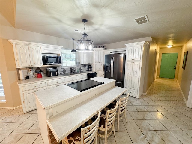 kitchen with sink, backsplash, decorative light fixtures, a kitchen island, and black appliances