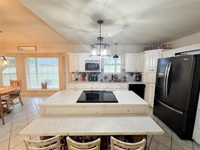 kitchen featuring decorative backsplash, white cabinetry, a kitchen island, and black appliances