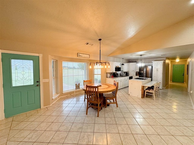 dining area featuring a textured ceiling, light tile patterned flooring, and vaulted ceiling