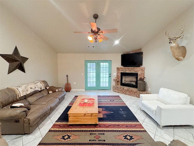 living room featuring ceiling fan, light tile patterned floors, a fireplace, and vaulted ceiling