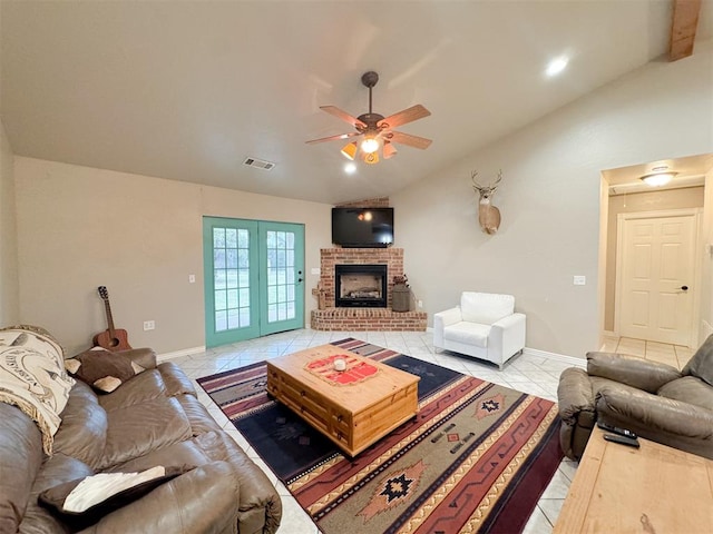 tiled living room with ceiling fan, vaulted ceiling, and a brick fireplace