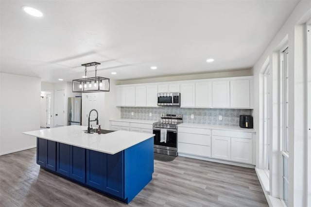 kitchen featuring white cabinets, decorative light fixtures, sink, and appliances with stainless steel finishes