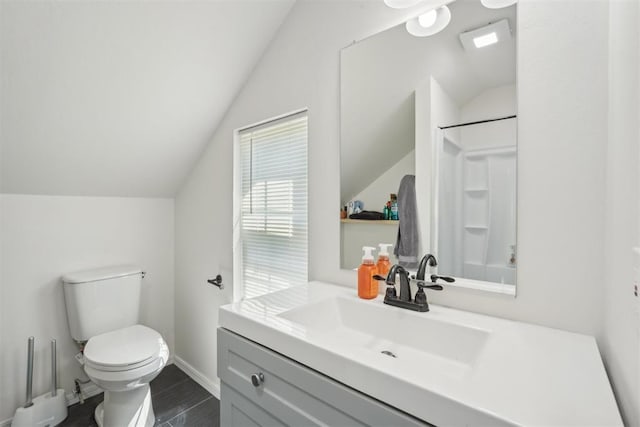 bathroom featuring hardwood / wood-style flooring, vanity, toilet, and vaulted ceiling