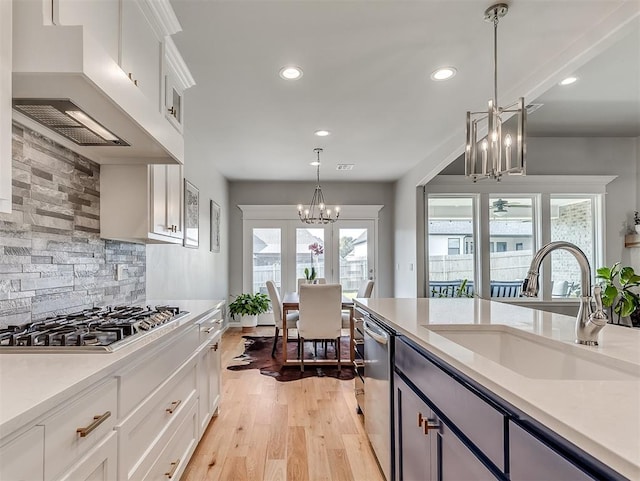 kitchen featuring pendant lighting, white cabinets, sink, and premium range hood