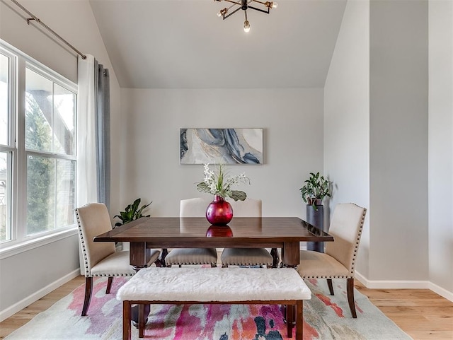 dining space with light hardwood / wood-style flooring, a healthy amount of sunlight, and lofted ceiling