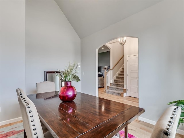 dining area featuring hardwood / wood-style floors, a chandelier, and lofted ceiling